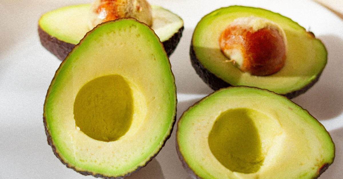Halved ripe avocados with the seed pit still inside one half